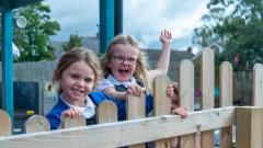 Two girls looking over a fence in the playground