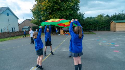 Group of girls in the playground playing with a parachute